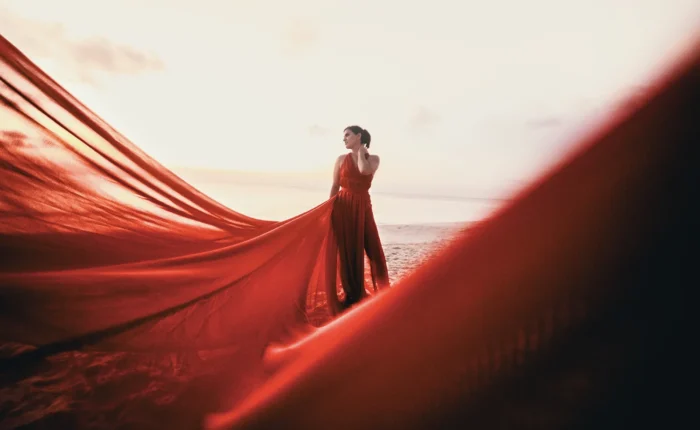 A coastal portrait in Riviera Maya, capturing a flying dress photoshoot with the fabric train lifted by the coastal wind.